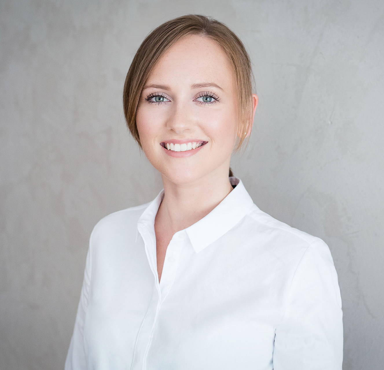 Frau in weißer Bluse vor Wand